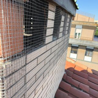 Rete anti-volatili sulle aperture di un torrino in muratura con più canne fumarie