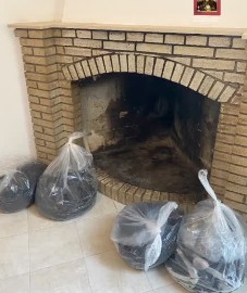 Caminetto in mattoni con i sacchi della fuliggine tolta dalla canna fumaria