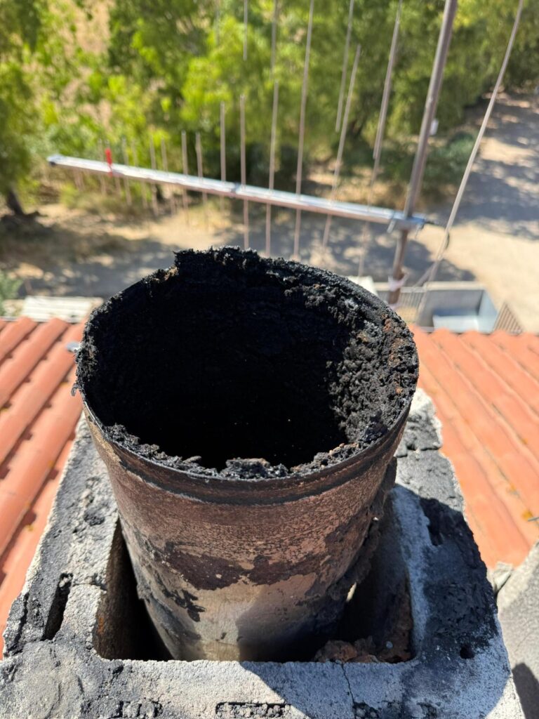 Canna fumaria in acciaio piena di fuliggine e catrame sul tetto