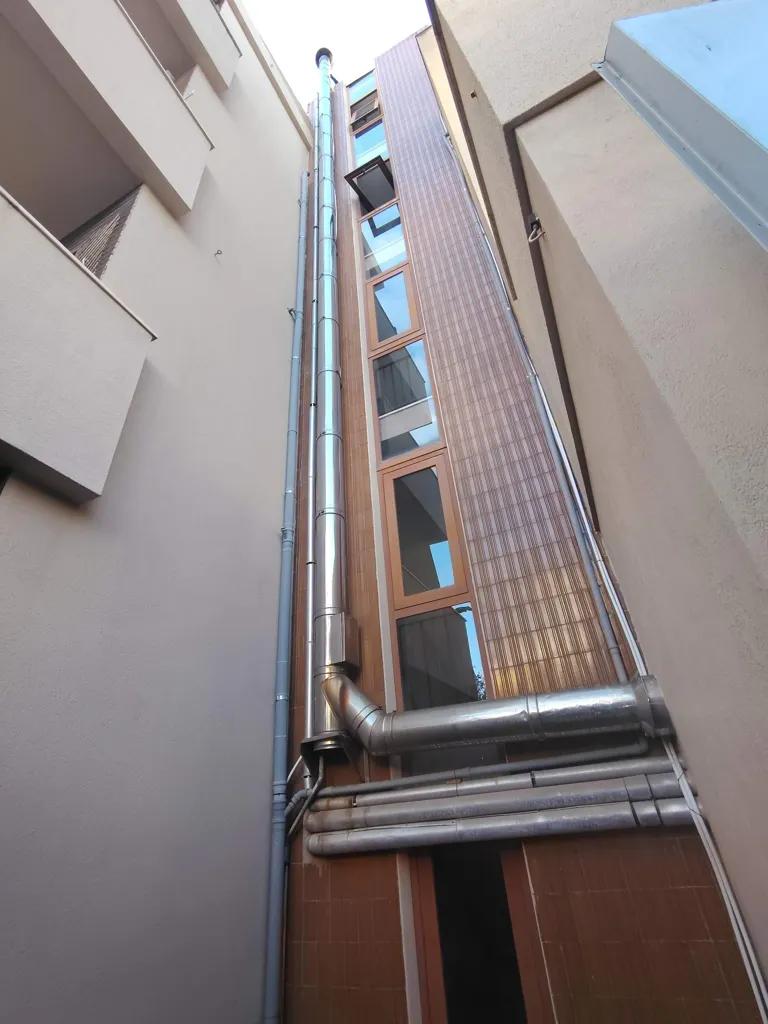 Canna fumaria in acciaio inox lungo la facciata interna di un condominio