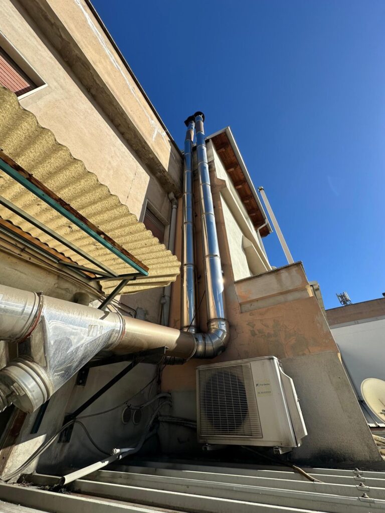 Due canne fumarie in acciaio inox lungo la facciata di un edificio