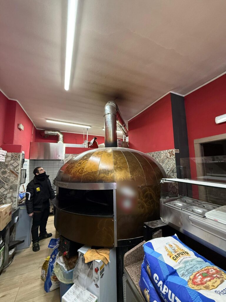 Spazzacamino controlla la canna fumaria del forno a legna di una pizzeria