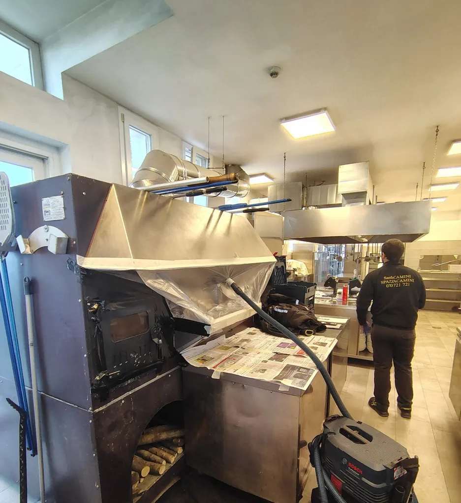 Forno a legna di un ristorante con la cappa protetta da pellicola e aspiratore