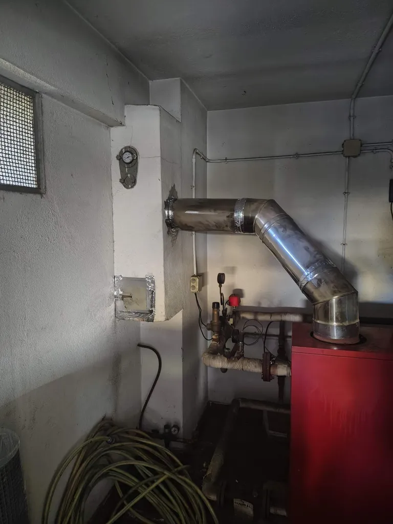 Locale caldaia con la caldaia e il raccordo in acciaio verso la canna fumaria