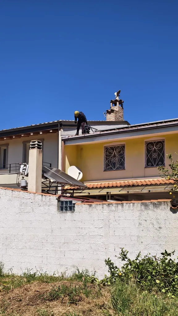 Spazzacamino con casco e imbracatura durante la pulizia della grondaia