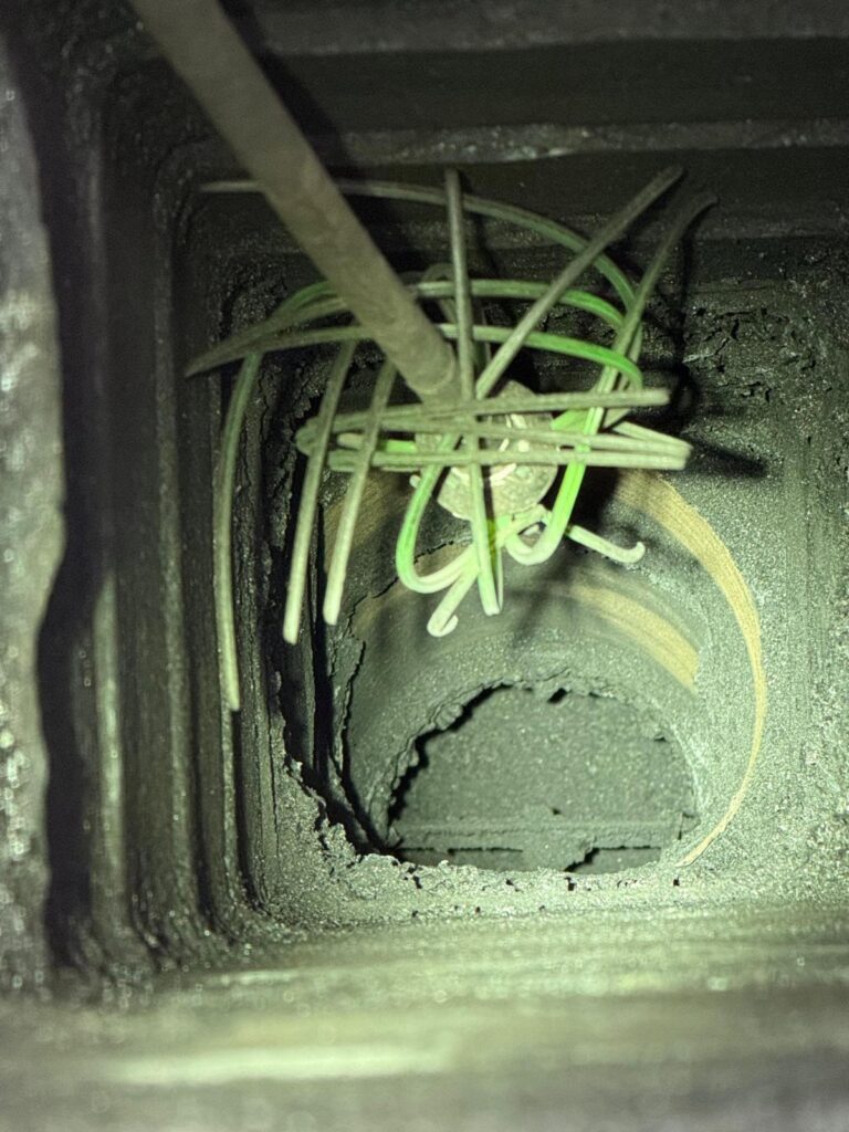Scovolo dentro la canna fumaria durante la pulizia