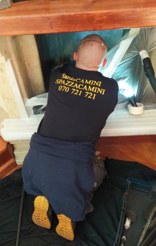 Spazzacamino con mascherina durante la pulizia di un caminetto protetto con pellicola