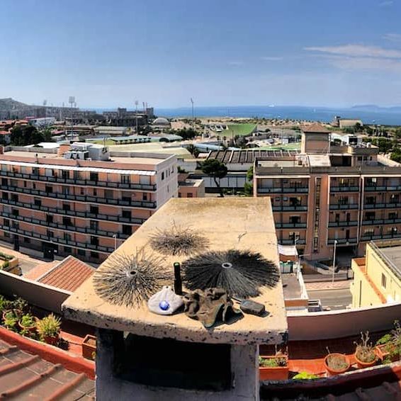 Spazzole da spazzacamino appoggiate su un comignolo a Cagliari